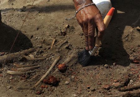 A police officer uses a brush to excavate a human skeleton at a construction site in the former war zone in Mannar