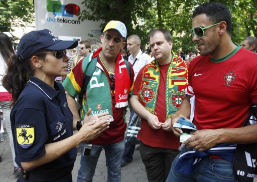 A Portuguese police officer speaks with Portuguese soccer fans as she patrols area in central Lviv
