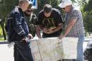 Ukrainian Ministry Emergency officer, left, Donetsk People's Republic fighter, 2nd left, and members of the OSCE mission in Ukraine examine a map as they discuss the situation around the site of the crashed Malaysia Airlines Flight 17 in the city of Donetsk, eastern Ukraine Sunday, July 27, 2014. A team of international police officers that had been due to visit the site of the Malaysian plane disaster in eastern Ukraine cancelled the trip Sunday after receiving reports of fighting in the area. Alexander Hug, the deputy head of a monitoring team from the OSCE in Europe, said it would be too dangerous for the unarmed mission to travel to the site from its current location in the rebel-held city of Donetsk. (AP Photo/Dmitry Lovetsky)