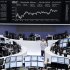 Traders work at their desks in front of the Dax board at the Frankfurt stock exchange