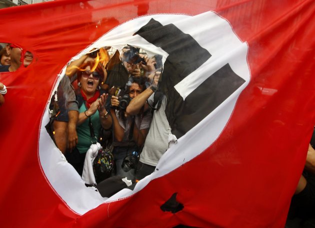 Demonstrators burn a flag emblazoned with a swastika during a demonstration against the visit of German Chancellor Angela Merkel in central Athens, October 9, 2012. Germany's Angela Merkel arrived in Greece on her first visit since Europe's debt crisis erupted here three years ago, braving protests to deliver a message of support - but no new money - to a nation hammered by recession and fighting to stay in the euro.     REUTERS/Yannis Behrakis (GREECE  - Tags: POLITICS BUSINESS TPX IMAGES OF THE DAY)