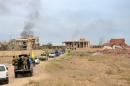 Iraqi security forces and Shiite fighters from the Popular Mobilisation units drive down a road surrounded by damaged houses, in the northern Iraqi city of Tikrit on March 31, 2015
