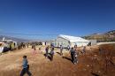 Syrian refugee children walk outside a tent being used as a school at a Syrian refugees camp in the Lebanese village of Baaloul on December 16, 2014
