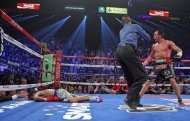 Referee Kenny Bayless (C) holds back Juan Manuel Marquez (R) as Manny Pacquiao lies face down on the mat after being knocked out by Marquez, on December 8, at the MGM Grand Garden in Las Vegas, Nevada