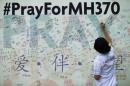 A woman writes a message on a board for family members of passengers onboard the missing Malaysia Airlines Flight MH370 at the MCA headquarters in Kuala Lumpur