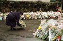 FILE - In this March 17, 1996 file photo, Britain's Queen Elizabeth places a floral bouquet with hundreds of others in front of Dunblane Primary School. In March 1996, a 43-year-old man named Thomas Hamilton walked into a primary school in this central Scotland town of 8,000 people and shot to death 16 kindergarten-age children and their teacher with four legally held handguns. In the weeks that followed, people in the town formed the Snowdrop campaign - named for the first flower of spring - to press for a ban on handguns. Within weeks, it had collected 750,000 signatures. By the next year, the ban had become law. (AP Photo/Ian Waldie, Pool-File)
