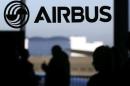People are silhouetted past a logo of the Airbus Group during the Airbus annual news conference in Colomiers