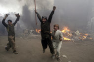 Pakistani men, part of an angry mob, react after burning belongings of Christian families, in Lahore, Pakistan, Saturday, March 9, 2013. A mob of hundreds of people in the eastern Pakistani city of Lahore attacked a Christian neighborhood Saturday and set fire to homes after hearing accusations that a Christian man had committed blasphemy against Islam's prophet, said a police officer. (AP Photo/K.M. Chaudary)