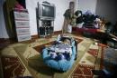 A Syrian refugee baby lies in his cradle on the floor as his mother takes part in an interview with Reuters in Istanbul