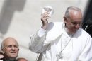 Pope Francis holds his skull cap as he arrives to lead his Wednesday general audience in San Peter's square at the Vatican