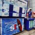 Man carries a bag with ice past a cooler with an advertisement for est sodas in Bangkok