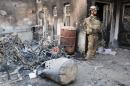 A member of the Iraqi security forces stands outside a burnt house on May 21, 2014 in the city of Ramadi