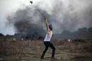 A Palestinian protester uses a slingshot to throw stones towards Israeli soldiers during clashes near the border fence between Israel and the central Gaza Strip east of Bureij on October 15, 2015