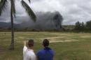 In this May 17, 2015 photo, a man and woman look toward smoke rising from a Marine Corps Osprey aircraft after making a hard landing on Bellows Air Force Station near Waimanalo, Hawaii. The fatal crash of the Marine Corps' new hybridized airplane-and-helicopter aircraft during a training exercise is renewing safety concerns about the machine. (Zane Dulin via AP)