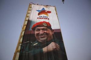 Os defensores da Venezuela & # 39; falecido presidente Hugo Chávez exibir sua imagem em um banner em um edifício, durante o primeiro aniversário da sua morte, em Caracas