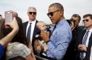 U.S. President Barack Obama poses with a baby before boarding Air Force One as he departs from Moffett Field in Mountain View, California