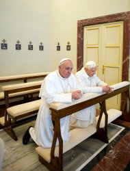 In this photo provided by the Vatican paper L'Osservatore Romano, Pope Francis, left, and Pope emeritus Benedict XVI pray together in Castel Gandolfo Saturday, March 23, 2013. Pope Francis has traveled to Castel Gandolfo to have lunch with his predecessor Benedict XVI in a historic and potentially problematic melding of the papacies that has never before confronted the Catholic Church. The Vatican said the two popes embraced on the helipad. In
 the chapel where they prayed together, Benedict offered Francis the traditional kneeler used by the pope. Francis refused to take it alone, saying "We're brothers," and the two prayed together on the same one. (AP Photo/Osservatore Romano, HO)