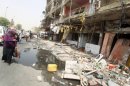 An Iraqi woman walks past destroyed shops on August 1, the day after a car bomb killed 12 in Baghdad