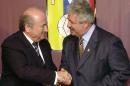 FILE - In this Nov. 8, 2004 file photo Sepp Blatter, President of the FIFA, left, shakes hands with the President of the Venezuelan Soccer Federation, Rafael Esquivel, in Caracas, Venezuela. Switzerland's justice ministry said on Monday, March 7, 2016, that the former Venezuela soccer federation president, Rafael Esquivel, has been extradited to face bribery charges in the United States in the widening FIFA case. (AP Photo/Leslie Mazoch, File)