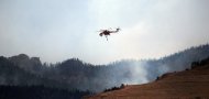 A helicopter participating in fire containment flies over part of the Waldo Canyon fire in June 2012 in Colorado Springs, Colorado. The massive fire, which eased slightly with the help of cooler temperatures and lighter winds, has destroyed hundreds of homes and forced more than 35,000 people to flee. (AFP Photo/Spencer Platt)