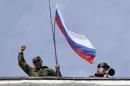 A man holds a Russian flag on the roof of the naval headquarters in Sevastopol