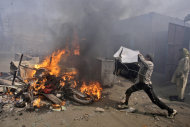 A Pakistani man, part of an angry mob, throws items taken from Christian houses into a fire in Lahore, Pakistan, Saturday, March 9, 2013. A mob of hundreds of people in the eastern Pakistani city of Lahore attacked a Christian neighborhood Saturday and set fire to homes after hearing accusations that a Christian man had committed blasphemy against Islam's prophet, said a police officer. (AP Photo/K.M. Chaudary)