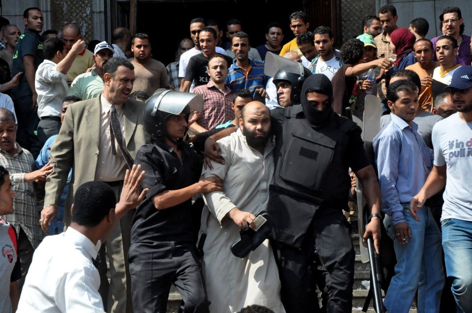 Egyptians security forces escort an Islamist supporter of the Muslim Brotherhood out of the al-Fatah mosque, after hundreds of Islamist protesters barricaded themselves inside the mosque overnight, following a day of fierce street battles that left scores of people dead, near Ramses Square in downtown Cairo, Egypt, Saturday, Aug. 17, 2013. Authorities say police in Cairo are negotiating with people barricaded in a mosque and promising them safe passage if they leave. Muslim Brotherhood supporters of Egypt's ousted Islamist president are vowing to defy a state of emergency with new protests today, adding to the tension. (AP Photo/Hussein Tallal)