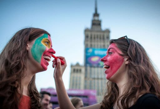 Portugal fans paint each other's faces in the Warsaw fan zone