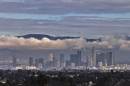 The San Gabriel Mountains are seen in the background during cloud cover over the Los Angeles skyline