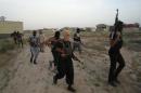 Masked Sunni gunmen walk with their weapons during a patrol outside the city of Falluja