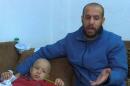 Syrian Refugee Jihad Alkhaled speaks to a reporter beside his son Mohammad in their home in Amman