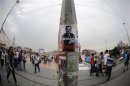 People walk past a poster depicting Turkish Prime Minister Tayyip Erdogan, put up by demonstrators, at Taksim Square in Istanbul