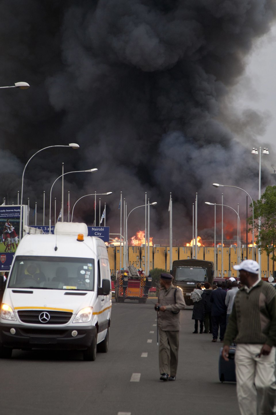 A policeman stands guard as a fire engulfs the International arrivals hall at the Jomo Kenyatta International Airport in Nairobi, Kenya Wednesday, Aug. 7, 2013. The Kenya Airports Authority said the Kenya's main international airport has been closed until further notice so that emergency teams can battle the fire. (AP Photo/Sayyid Azim)