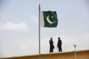 A Pakistani flag flies on a mast as paramilitary Frontier Corps soldiers talk while guarding at Karachi's District Malir prison