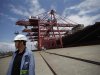 Employee stands next to container ship at Ningbo port