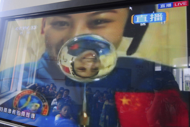 Elementary school students are reflected on the screen of a television showing a lecture delivered by Chinese female astronaut Wang Yaping onboard the Tiangong 1 prototype space station, in Taizhou in eastern China's Zhejiang province Thursday June 20, 2013. China held its first classroom lecture from its orbiting space station as part of efforts to popularize the successful manned space flight program among young people. (AP Photo) CHINA OUT