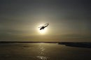 A helicopter flies over Arctic ice towards the Applied Physics Laboratory Ice Station during an exercise north of Prudhoe Bay