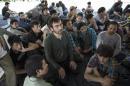 Suspected Uighurs from China's region of Xinjiang, sit inside a temporary shelter after they were detained near the Thailand-Malaysia border in Hat Yai