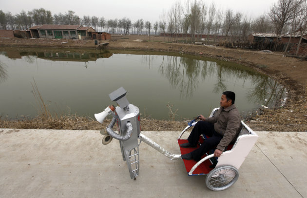 Farmer Wu Yulu, 48, rides in a cart pulled by his walking robot near his home in a village at the outskirts of Beijing