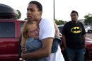 FILE - In this Friday, July 20, 2012 file photo, Judy Goos, left, hugs her daughter's friend, Isaiah Bow, 20, an eyewitnesses, as Terrell Wallin, 20, right, looks on, outside Gateway High School where witnesses were brought for questioning after a gunman opened fire at the midnight premiere of the "Dark Knight Rises" movie in Aurora, Colo. After fleeing the theater, Bow returned to find his girlfriend who turned out to be safe. "Very stupid I know, But I didn't want to leave her in there," says Bow. (AP Photo/Barry Gutierrez)