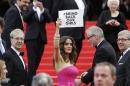 Actress Salma Hayek holds up a sign reading "bring back our girls", part of a campaign calling for the release of nearly 300 abducted Nigerian schoolgirls being held by Nigerian Islamic extremist group Boko Haram, as she arrives for the screening of Saint-Laurent at the 67th international film festival, Cannes, southern France, Saturday, May 17, 2014. (AP Photo/Thibault Camus)
