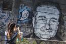 A woman takes a picture of a mural depicting late actor Robin Williams in Belgrade
