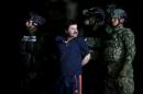 Joaquin "El Chapo" Guzman is escorted by soldiers during a presentation at the hangar belonging to the office of the Attorney General in Mexico City