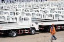 A worker walks past Chinese trucks for exporting at a port of Liangyungang