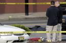 A person lays on the ground near evidence markers as officials investigate the scene where a Jersey City Police Department officer was shot and killed while responding to a call at a 24-hour pharmacy, Sunday, July 13, 2014, in Jersey City, N.J. Officer Melvin Santiago was shot in the head while still in his police vehicle as he and his partner responded to an armed robbery call at about 4.a.m., Jersey City Mayor Steven Fulop said in a statement. Fulop said officers responding to the robbery call shot and killed the man who shot Santiago. He was not immediately identified.(AP Photo/Julio Cortez)
