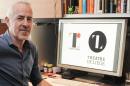 Belgian designer Olivier Debie poses in his office in Liege as his computer display shows Tokyo's 2020 Olympic emblem (L) and the logo of the Theatre de Liege on July 30, 2015