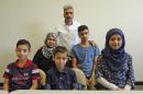 Nadim Fawzi Jouriyeh, rear, a Syrian refugee that arrived with his family in the United States this week, poses with the family Wednesday Aug. 31, 2016, in El Cajon, Calif. The family members are his wife Rajaa Abdo Altaleb, back left, son Mohammad Fawzi Jouriyeh, back right, daughter Hanan Nadim Jouriyeh, right, Farouq Nadim Jouriyeh, front center, and Hamzeh Nadim Jouriyeh, front left. San Diego's newest Syrian refugee arrivals include the Jouriyeh family of six from the city of Homs. The family tells the AP they feel welcome in their new community of El Cajon, where many refugees are resettled where store signs are in Arabic and many speak their language. (AP Photo/Lenny Ignelzi)