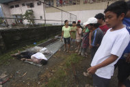 Residents look at bodies recovered from flashflood in New Bataan, Compostela Valley province, southern Philippines on Wednesday Dec. 5, 2012. The death toll from Typhoon Bhopa climbed to more than 100 people Wednesday, while scores of others remain missing in the worst-hit areas of the southern Philippines. (AP Photo/Karlos Manlupig)