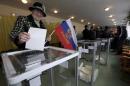 A woman holds a Russian flag as she casts her ballot during the referendum on the status of Ukraine's Crimea region at a polling station in Bakhchisaray