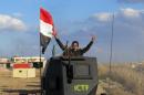 A member of Iraqi pro-governement forces flashes the sign of victory atop an armoured vehicle on February 8, 2016 in the Jwaibah area, on the eastern outskirts of Ramadi, after Iraqi troops retook it from Islamic State (IS) group jihadists